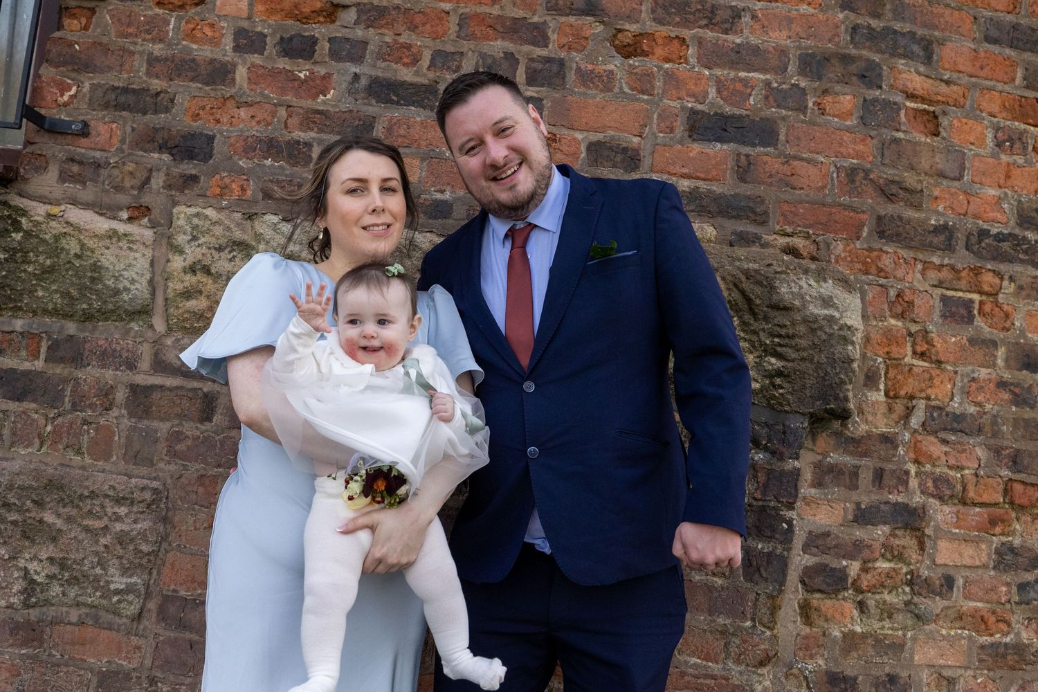 Wedding guests holding a baby during relaxed family portraits at Windmill Farm, Burscough following the Southport Town Hall wedding.