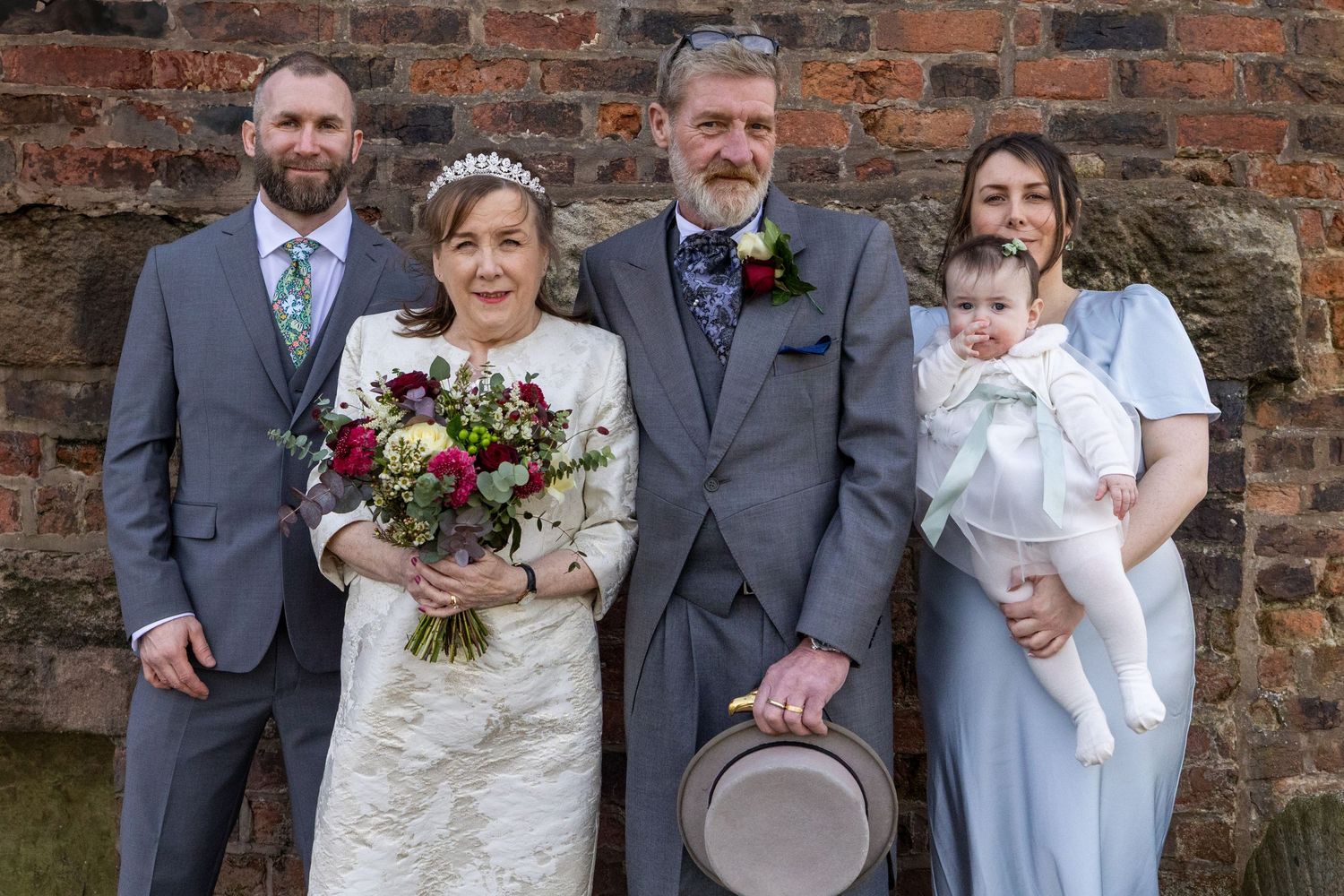 Bride and groom with their son, daughter  & baby granddaughter during relaxed family photos outside the brick wall at Windmill Farm,