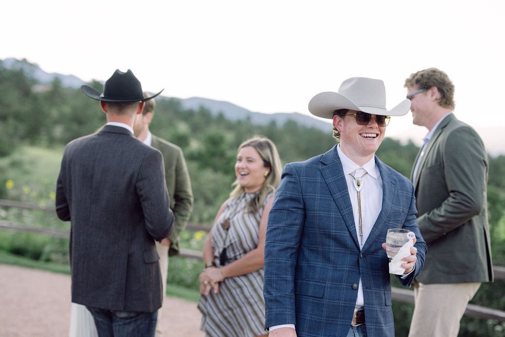 Wedding guests mingle and socialize outdoors during a reception celebration in a scenic natural setting.