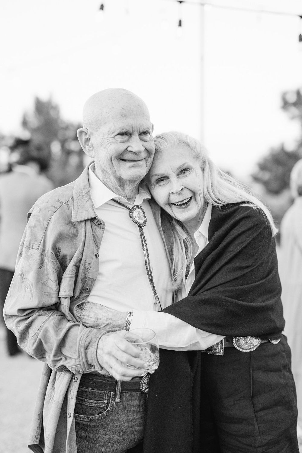 Black and white portrait of elderly couple embracing and laughing together.
