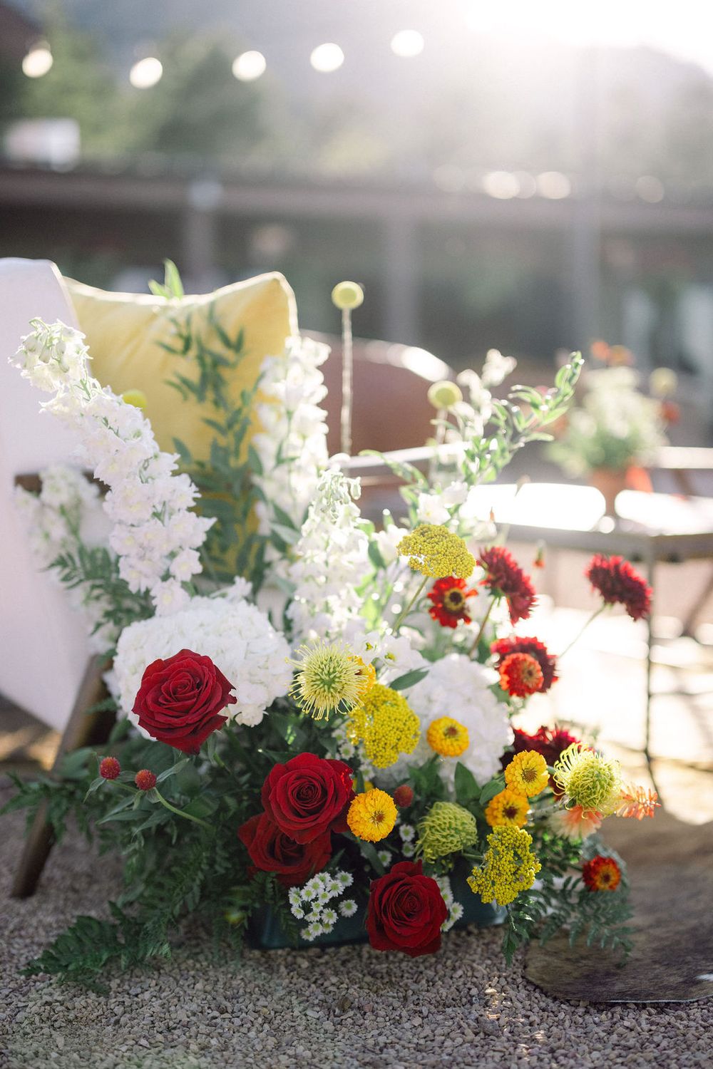 Colorful floral arrangements featuring red roses, yellow blooms and white flowers displayed in a row against a blurred background.
