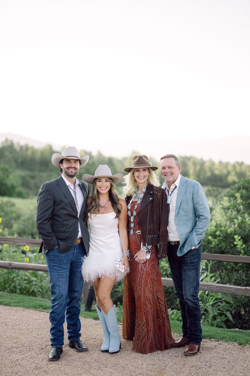 Family posing together outdoors in western attire with a natural landscape backdrop.
