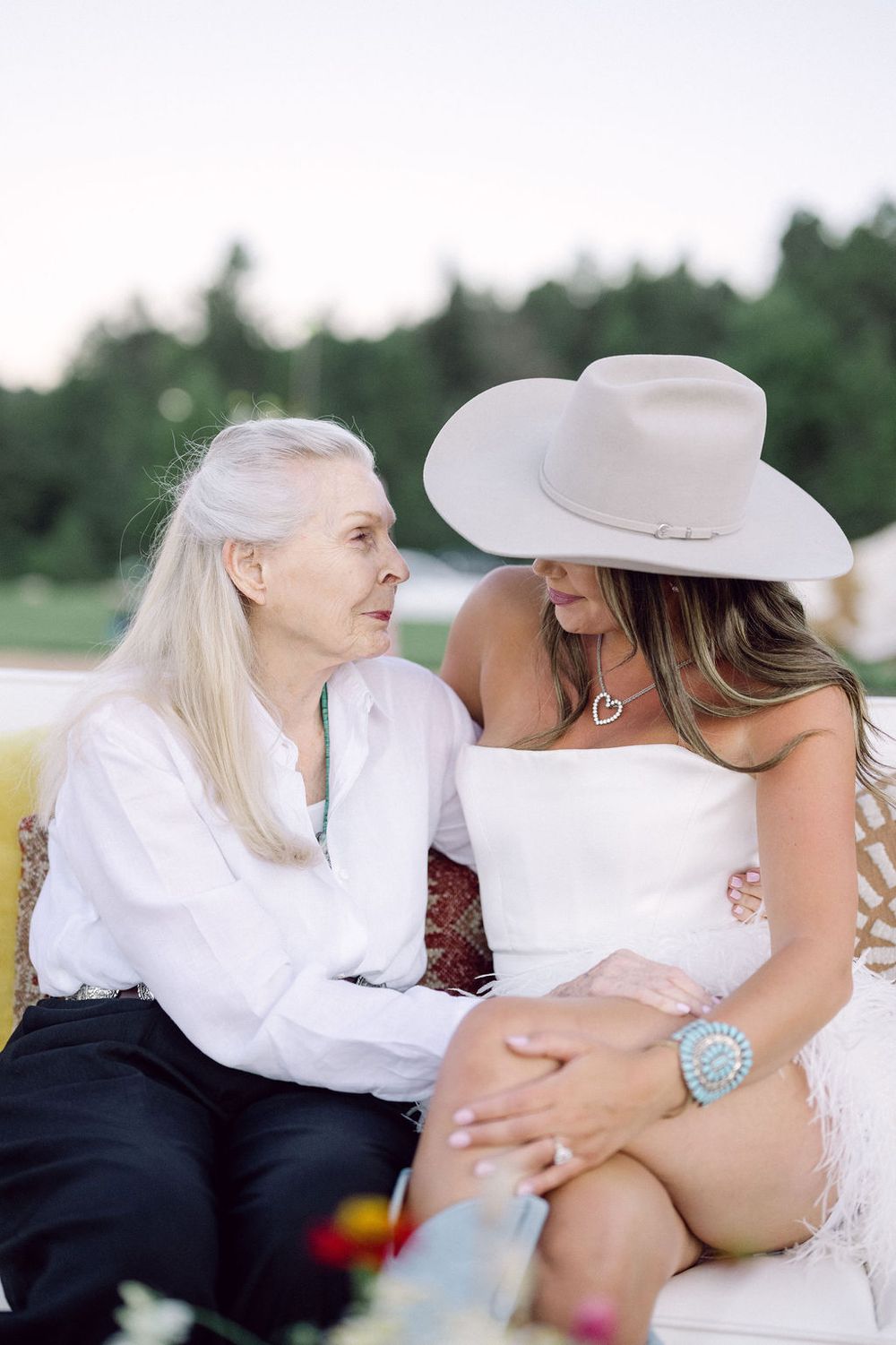 Intimate outdoor gathering with people wearing white and cowboy hats seated together.