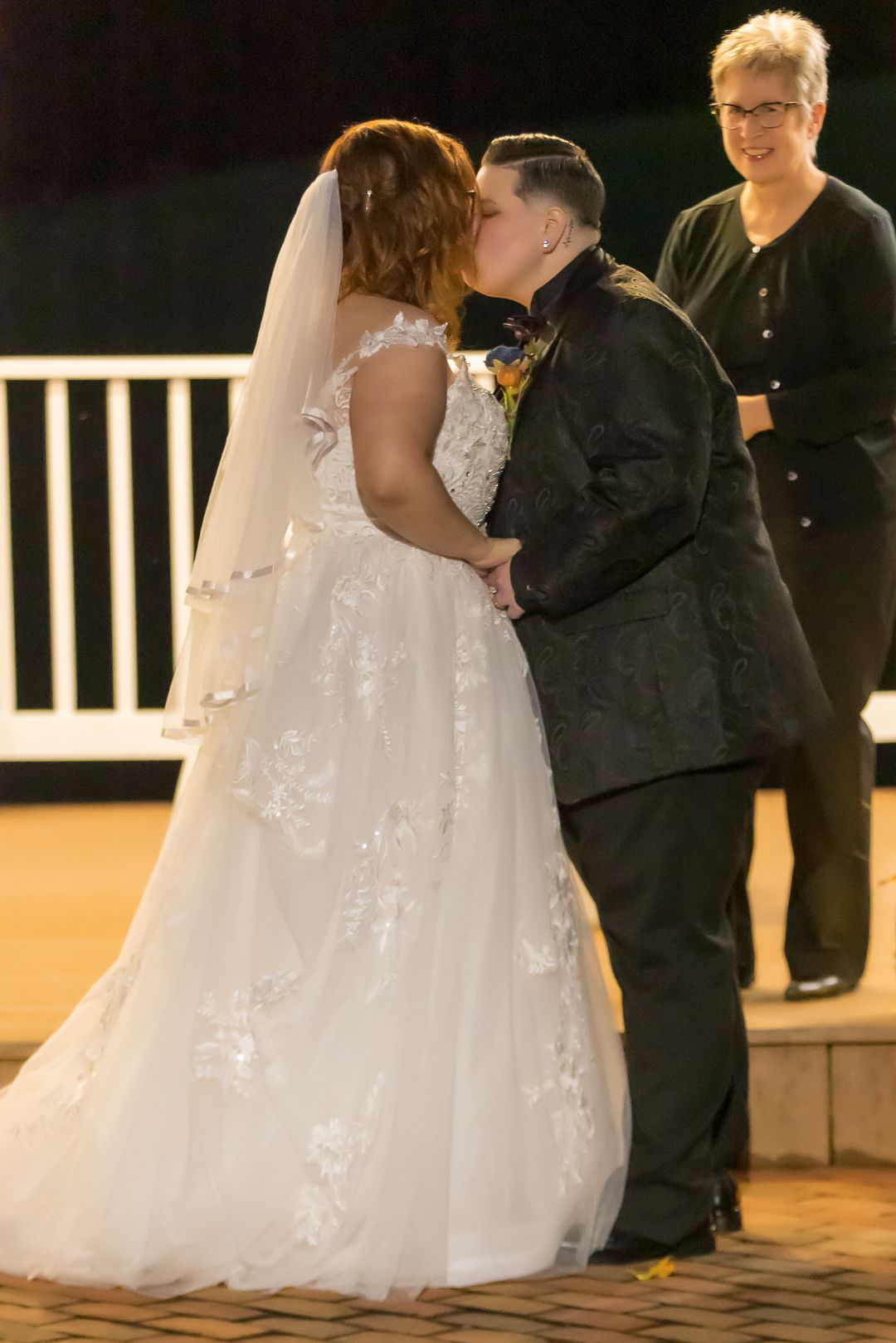 A couple shares a romantic dance at their wedding reception with a white gazebo in the background.