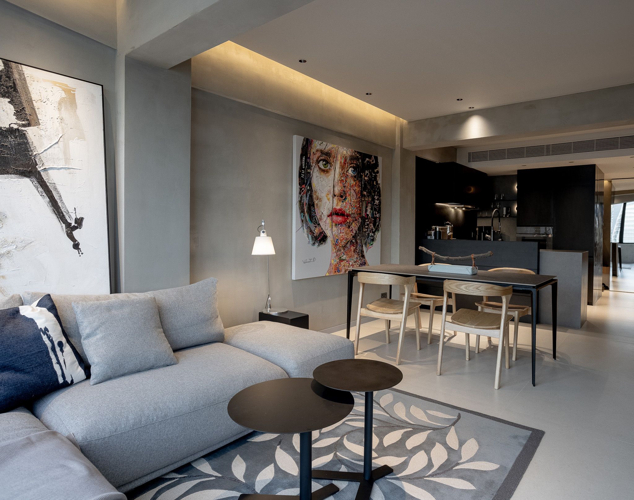 Modern open-plan living room with large portrait artwork, grey sofa and dining area.