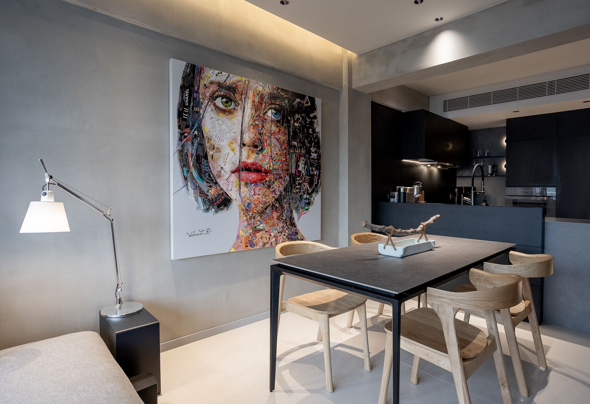 Contemporary dining area with colorful portrait wall art, black table, wooden chairs, and open kitchen beyond.