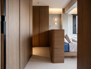 Elegant hallway with warm wood paneling leading to a softly lit bedroom with curved wooden partition wall.