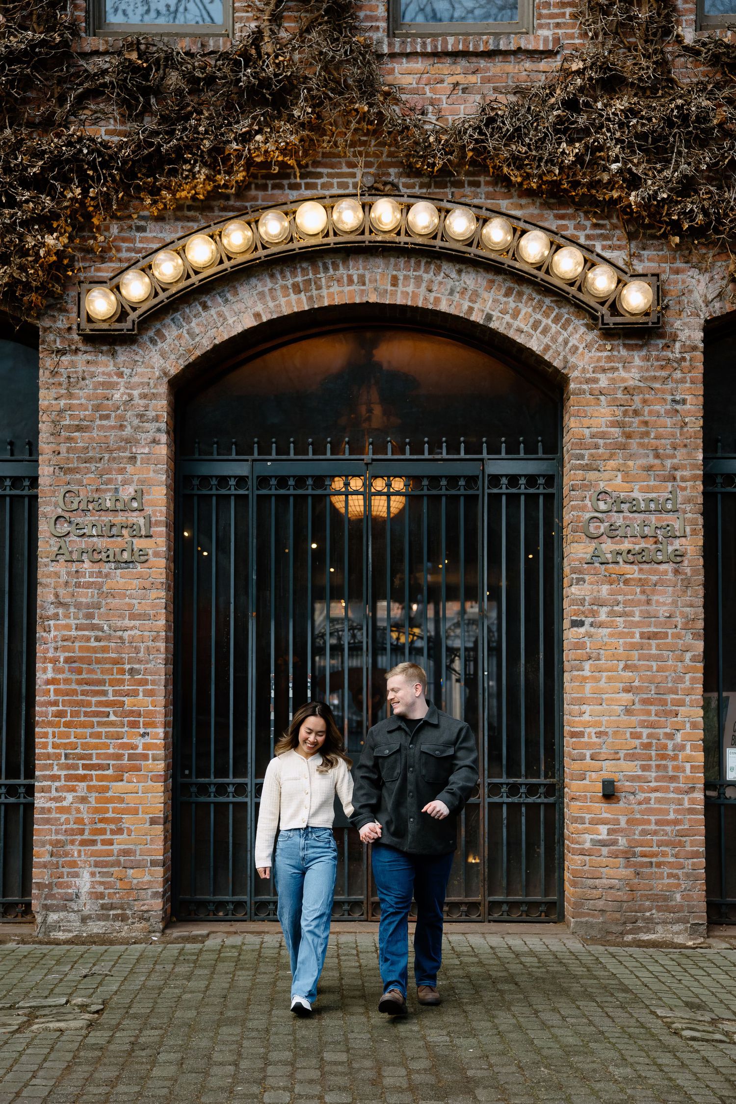 A romantic couple poses in front of a rustic brick archway with vintage lighting in a series of connected photos.