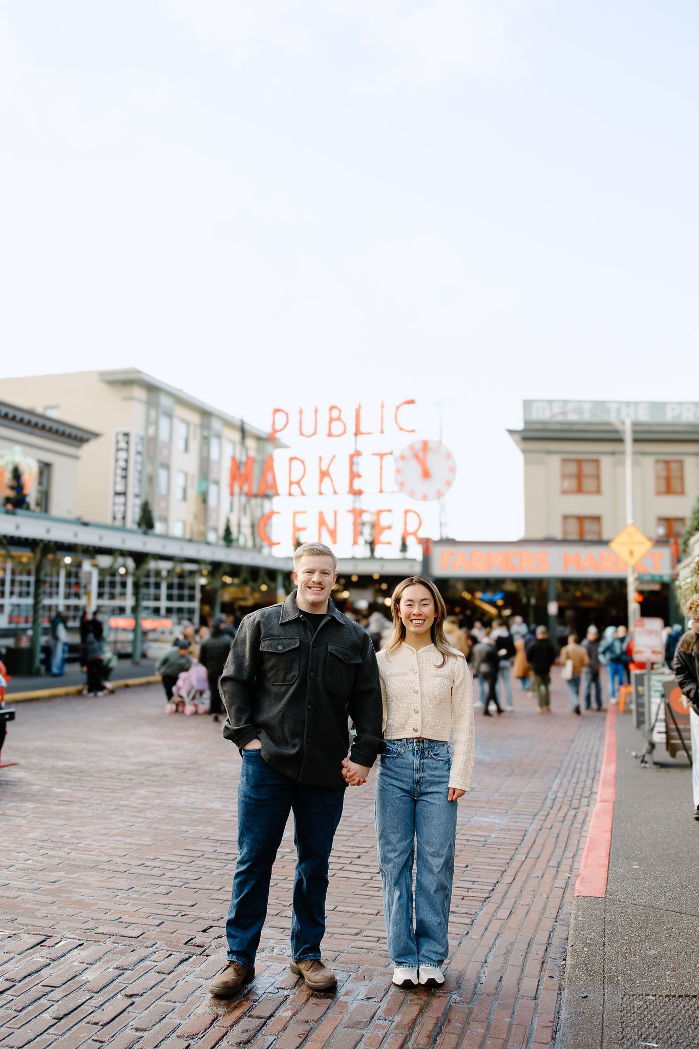 A couple walks together on cobblestone pavement at Pike Place Market in Seattle during daytime.