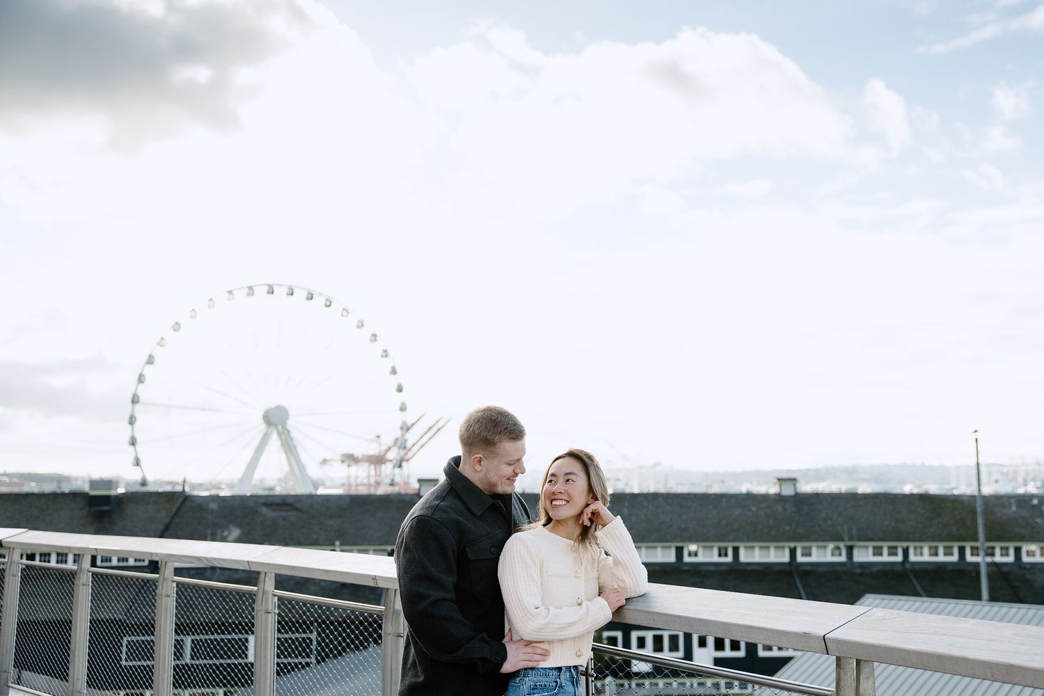 A couple shares a romantic moment on a rooftop terrace overlooking a cityscape at sunset.