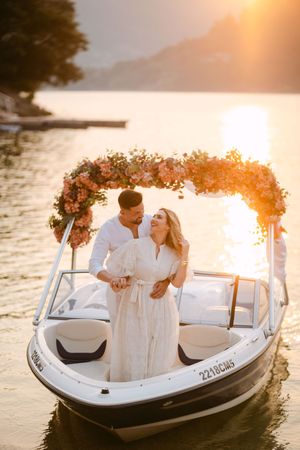 Romantic sunset boat ride with floral arch decorations over white speedboat on calm waters.