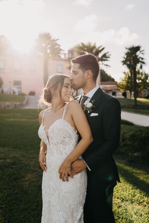 Golden hour wedding portraits in a garden setting with warm sunlight filtering through palm trees.