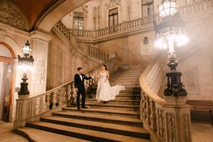 Ornate marble staircase with elegant balustrades and hanging lanterns in a grand historic building interior.