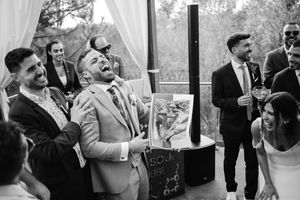 Wedding guests laugh joyfully during a reception celebration.