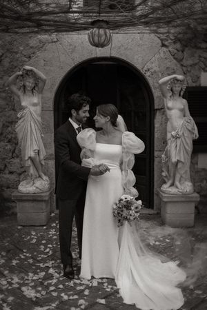 Black and white wedding photos showing a romantic garden ceremony with stone statues and scattered petals.