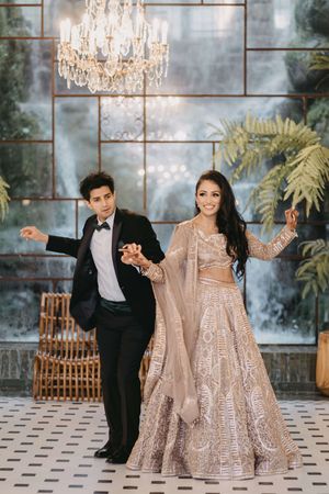 A couple in formal attire dances together in an elegant ballroom with crystal chandeliers and marble floors.