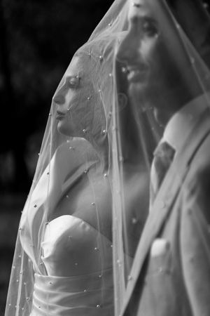 Artistic black and white close-up of a bride through her delicate veil.