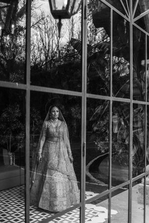 Vintage-style display of wedding dresses in a glass conservatory with dramatic lighting.