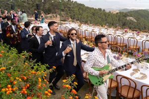 Panoramic view of an outdoor wedding reception with long tables set against a mountainous backdrop and orange flowers.