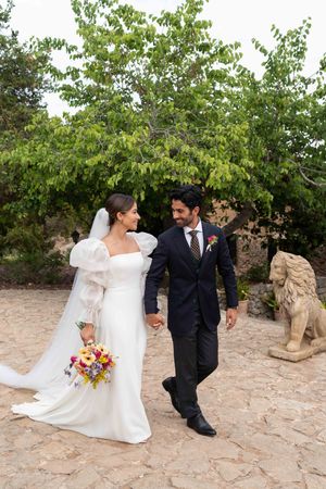 Wedding couple shares intimate moments on stone pathways surrounded by greenery.