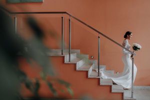 Wedding dress flowing down orange staircase in artistic architectural composition.