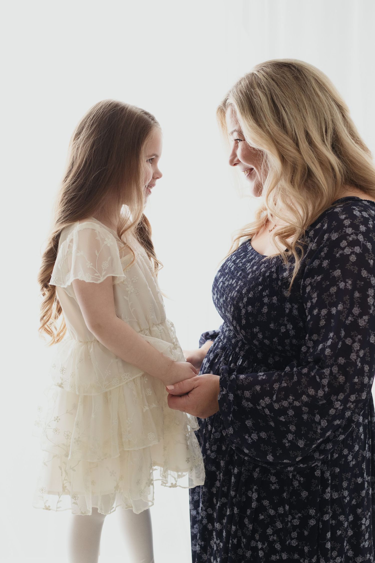 A series of tender moments between a child in a white lace dress and someone wearing a navy floral print dress.