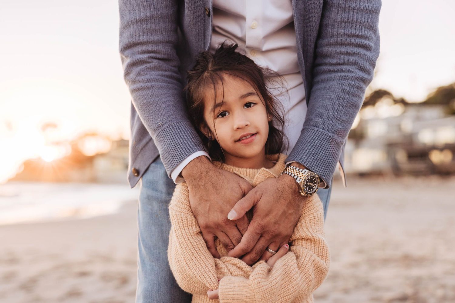 Parent and child share a tender moment together while playing on the beach at sunset.