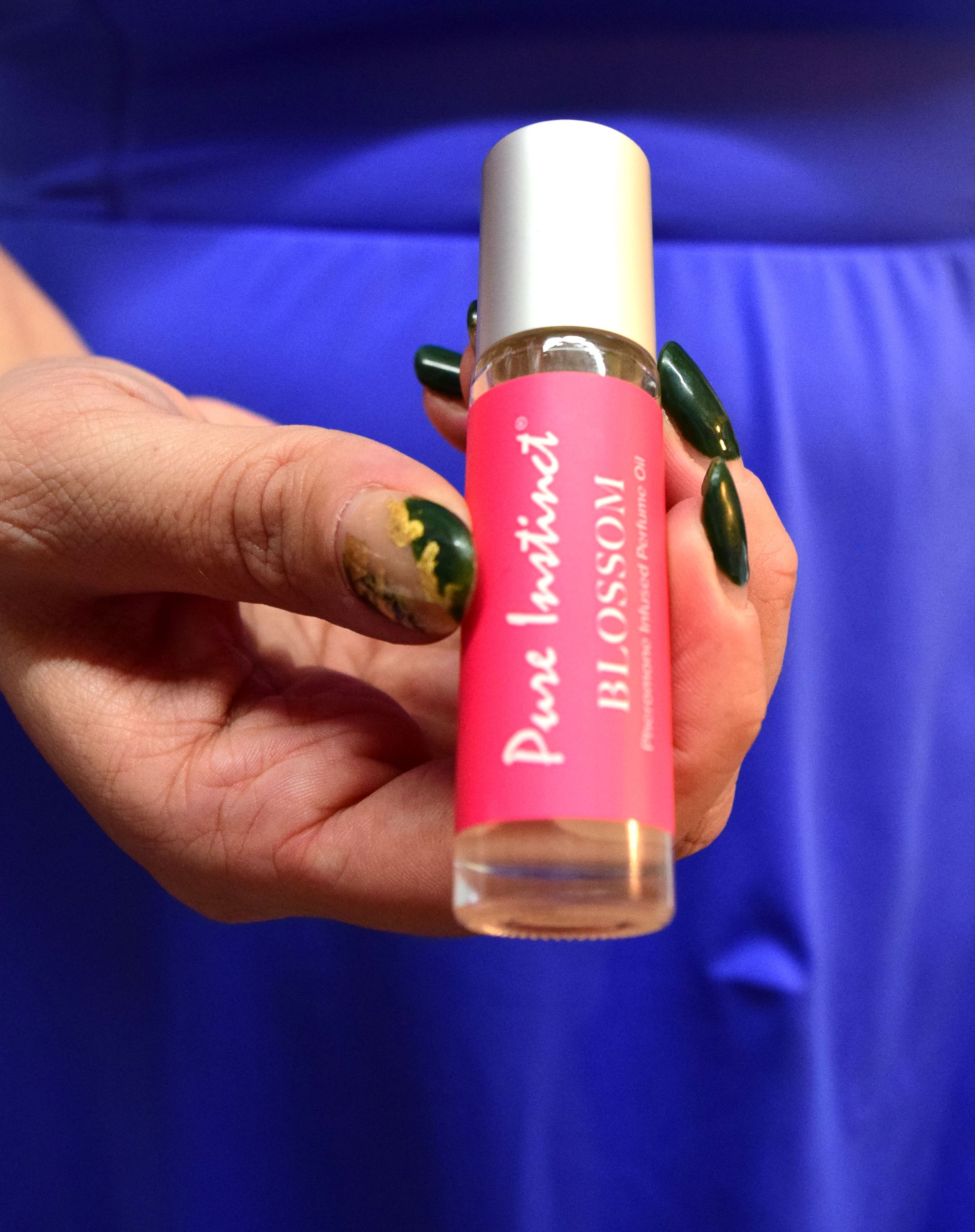 Pink cosmetic product bottles being displayed against a vibrant blue fabric background.