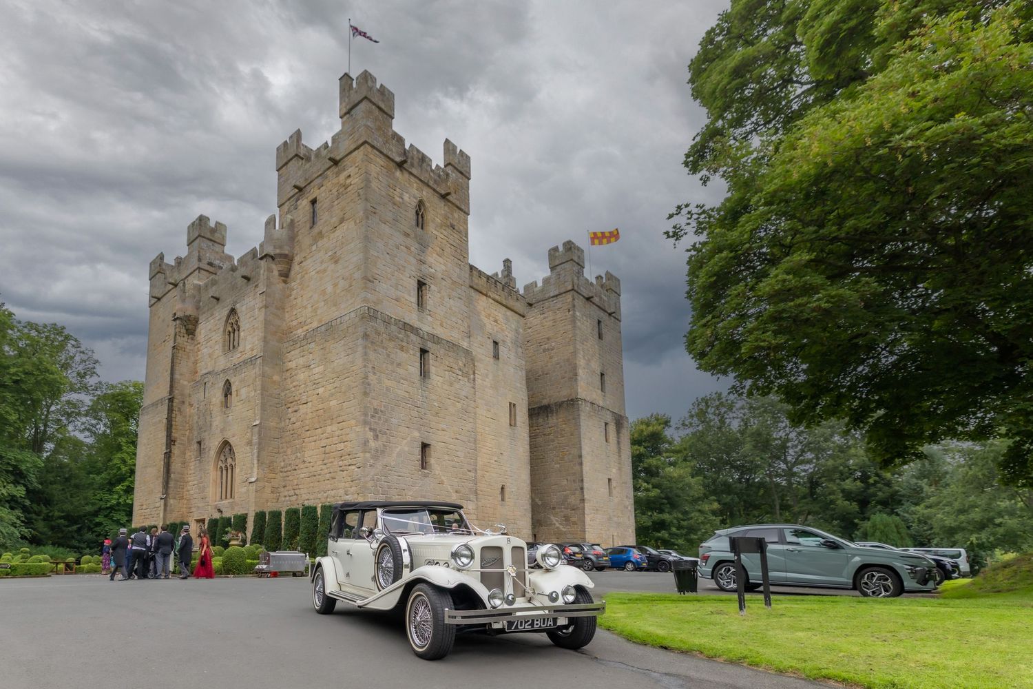 Historic castle exterior with gray stone towers and turrets stands against cloudy sky in Scottish countryside.