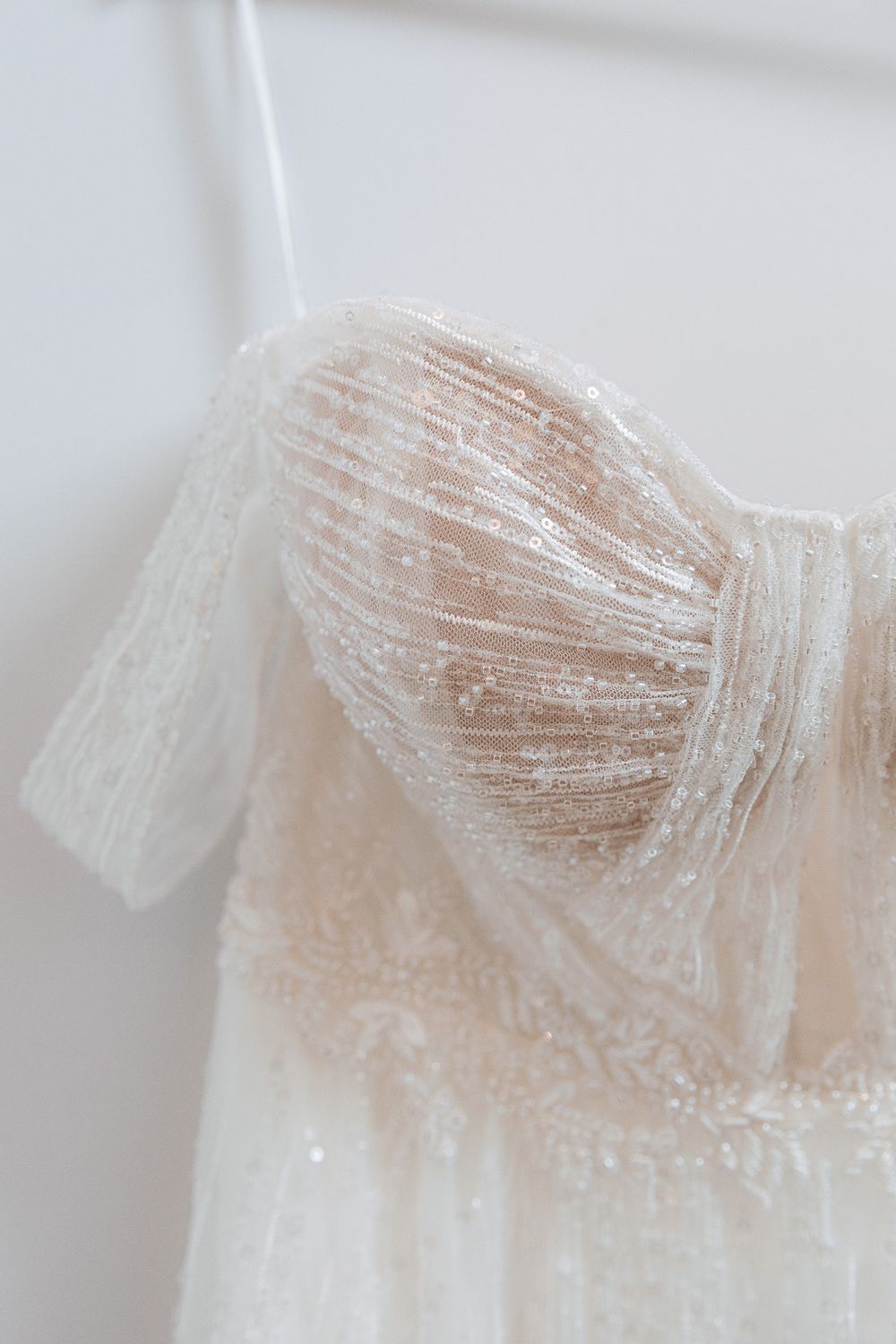 A delicate lace wedding dress bodice with sheer fabric and intricate beading details in soft white.