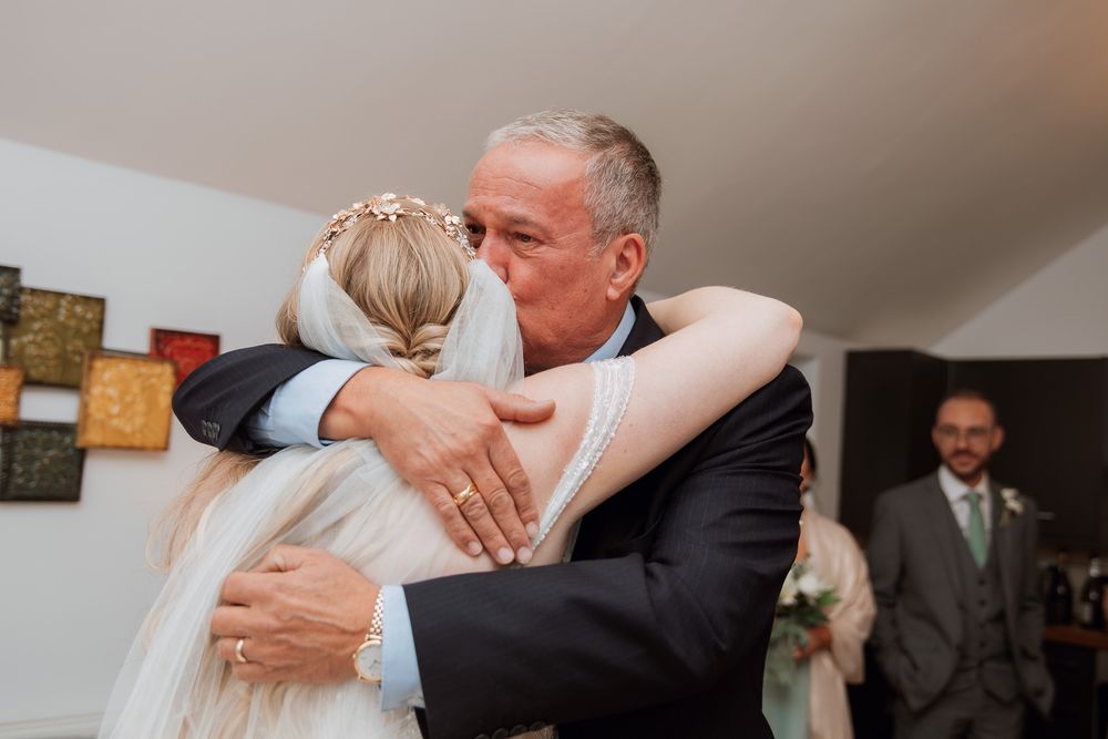 A tender embrace shared during an intimate wedding ceremony indoors.
