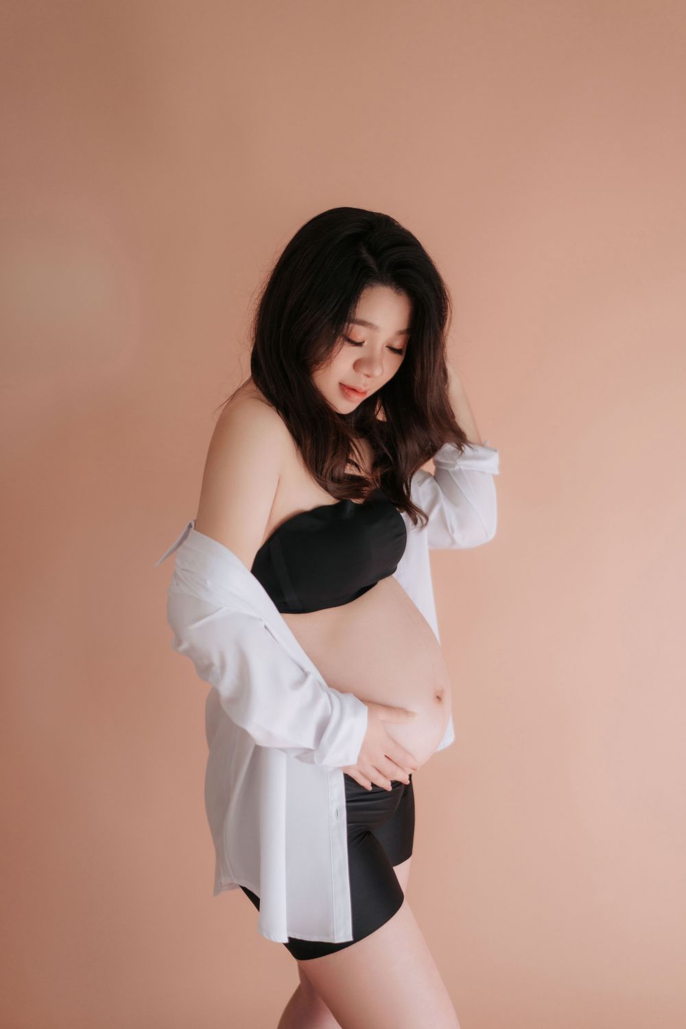 Artistic portrait series showing intimate moments of self-embrace against a soft peach-colored backdrop.藝術肖像系列，展現了在柔和的桃色背景下，人們自我擁抱的親密時刻。