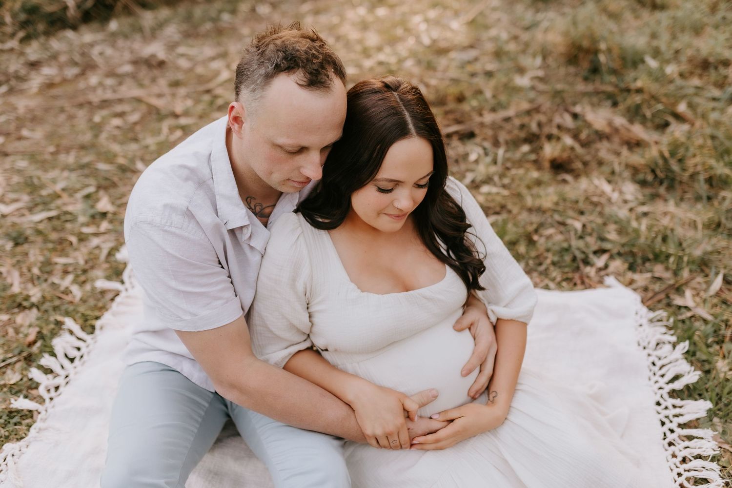 Family photoshoot outdoors with natural fall backdrop showing loving embraces and candid moments.