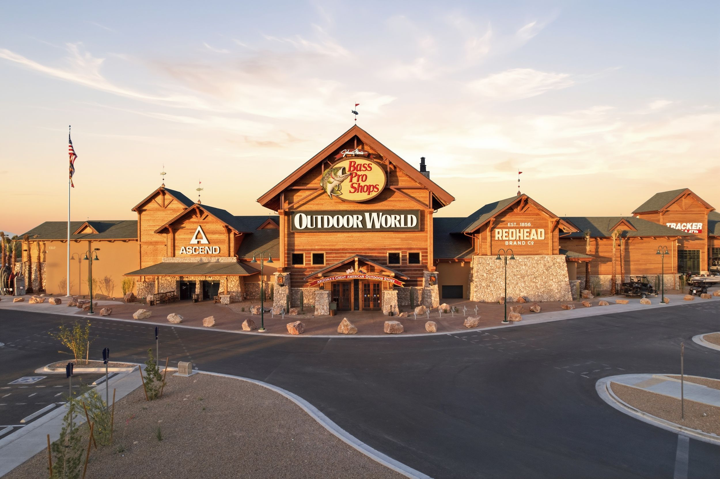 Bass Pro Shops Outdoor World retail store exterior at dusk with rustic wood facade and illuminated signage.