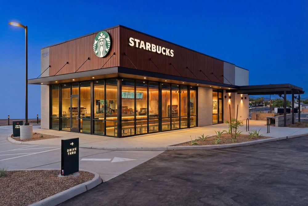A modern Starbucks coffee shop exterior with large windows and signage against a bright blue sky.
