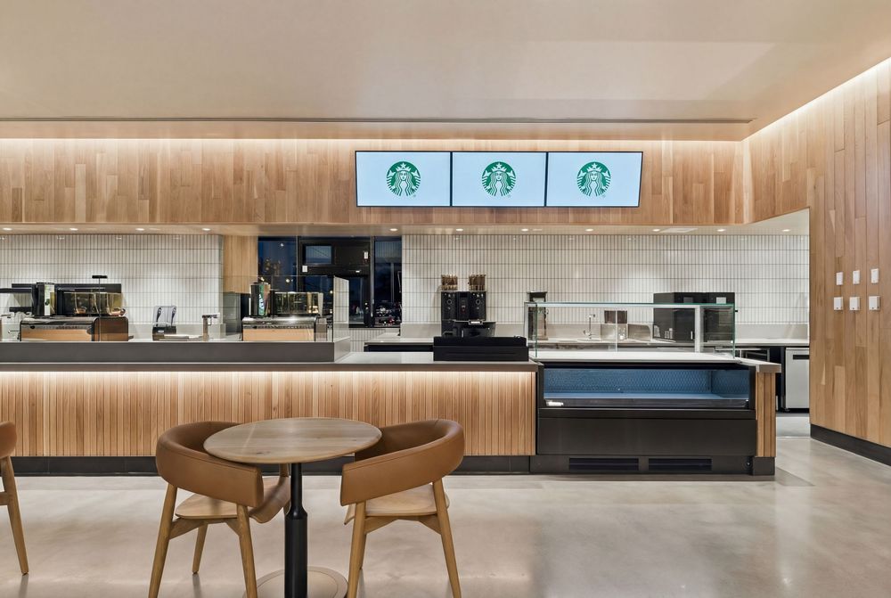 Modern Starbucks interior with wood paneling, digital menu displays, and minimalist furniture design.