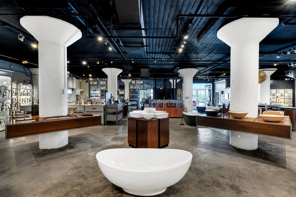 Modern office interior with white cylindrical columns and industrial ceiling features sleek furniture and open workspace design.