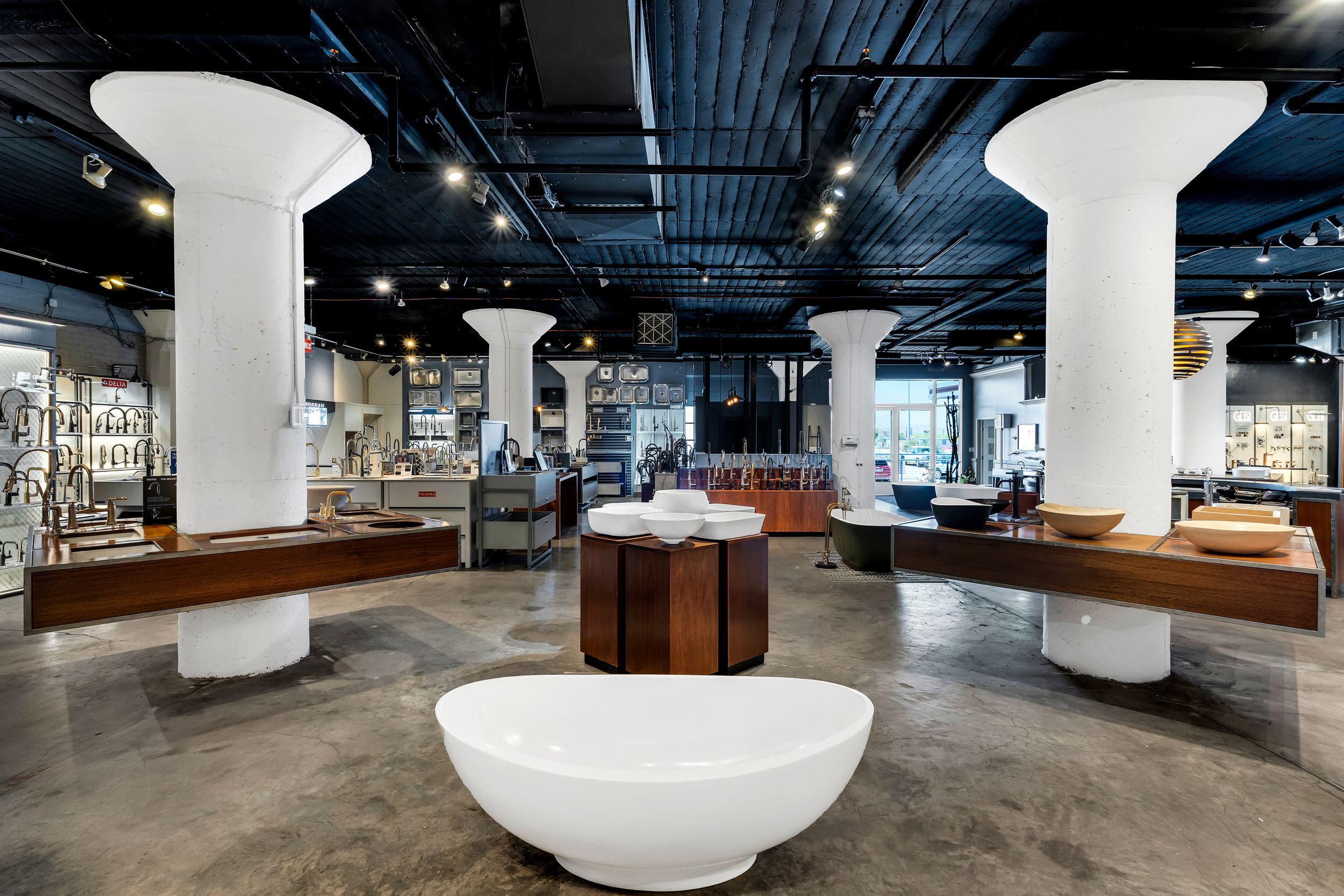 Modern office interior with white cylindrical columns and industrial ceiling features sleek furniture and open workspace design.