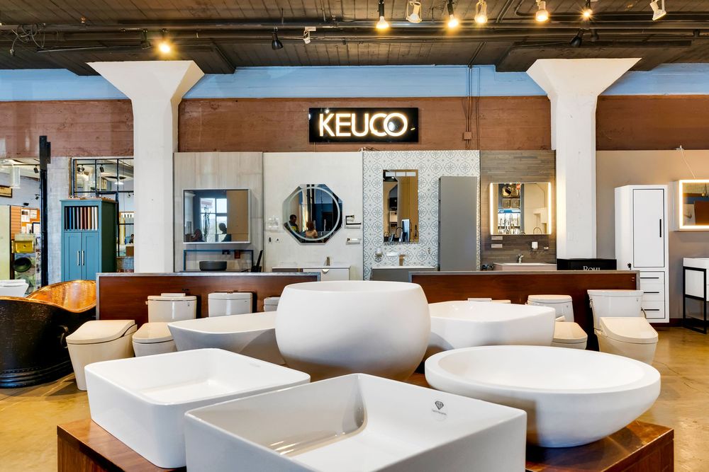 Modern bathroom showroom displays white freestanding bathtubs and fixtures under track lighting in an open retail space.