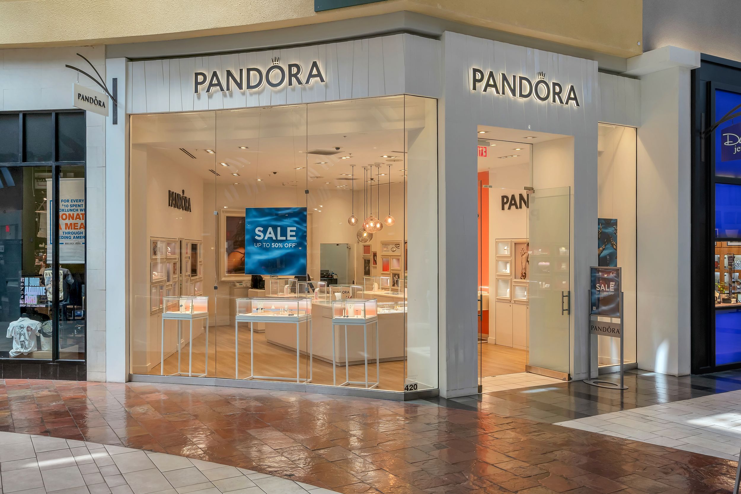 Pandora jewelry store exterior in a shopping mall with glass storefront displaying a sale sign and elegant showcases.