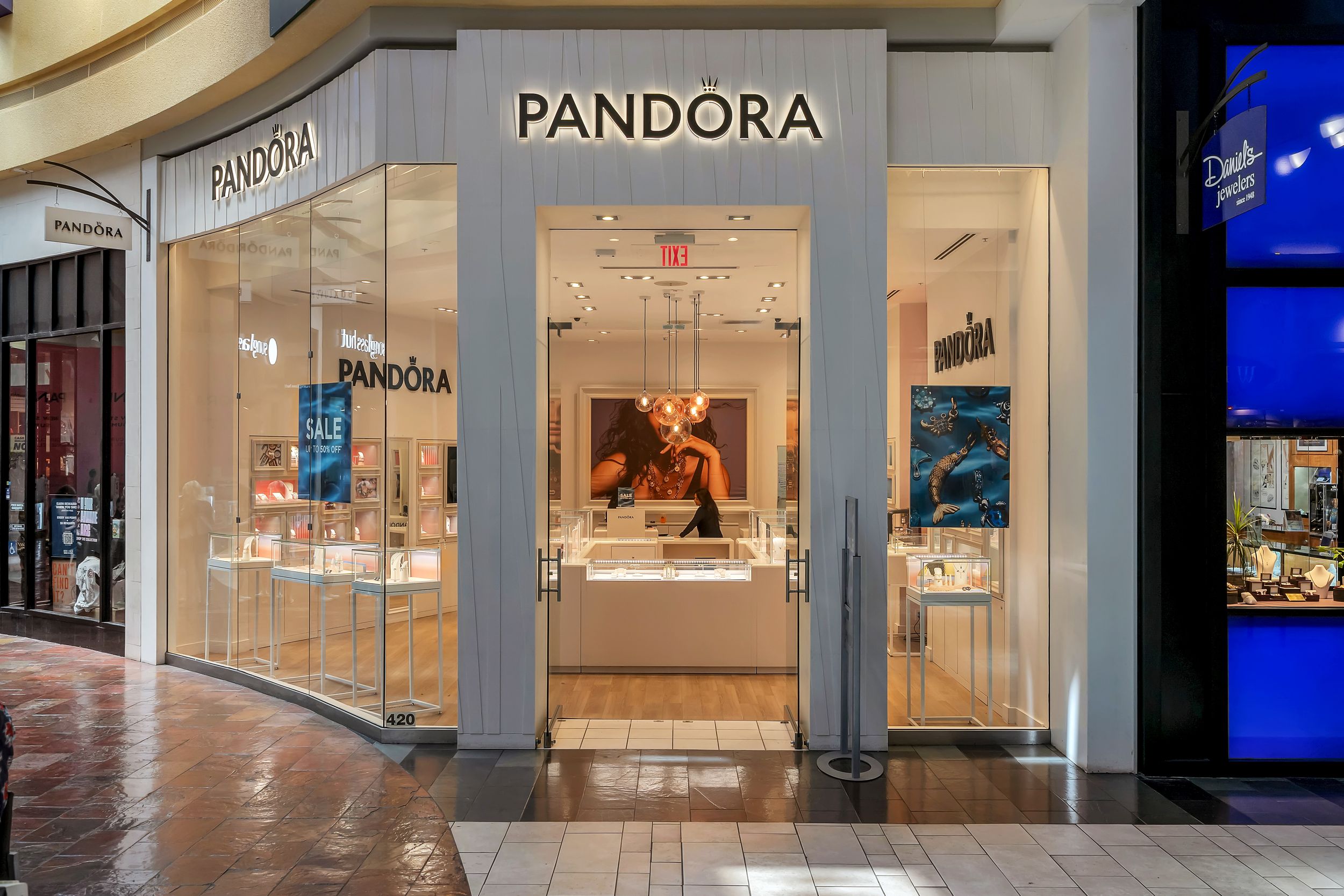 Pandora jewelry store front in a shopping mall with illuminated displays and elegant storefront design.