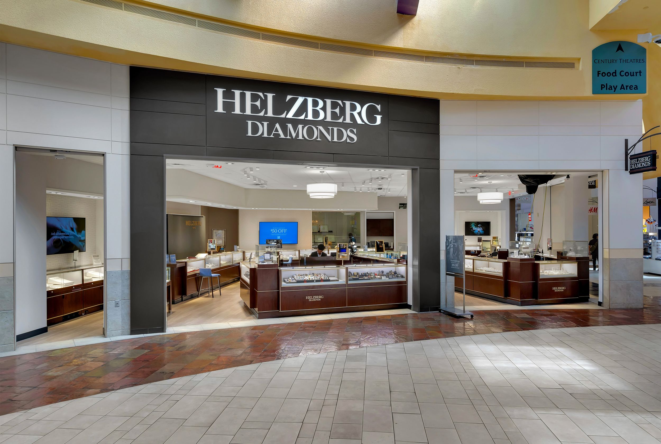Interior view of a Helzberg Diamonds jewelry store in a shopping mall, featuring glass display cases and bright lighting.