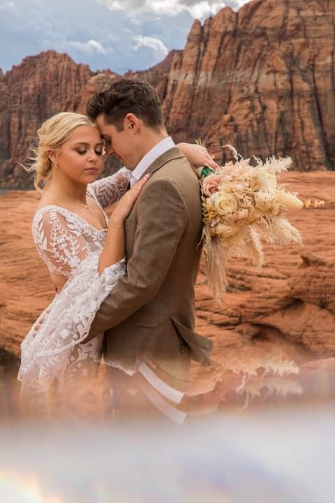 A romantic wedding photo series set against dramatic red rock formations in a desert landscape.