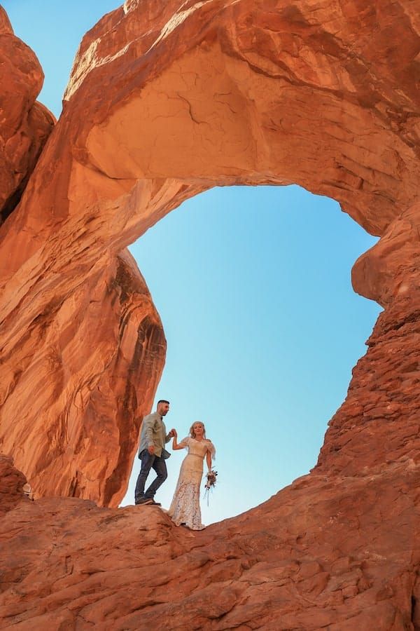 A sequence of photos showing silhouettes against a bright blue sky through a natural stone arch in red rock formations.