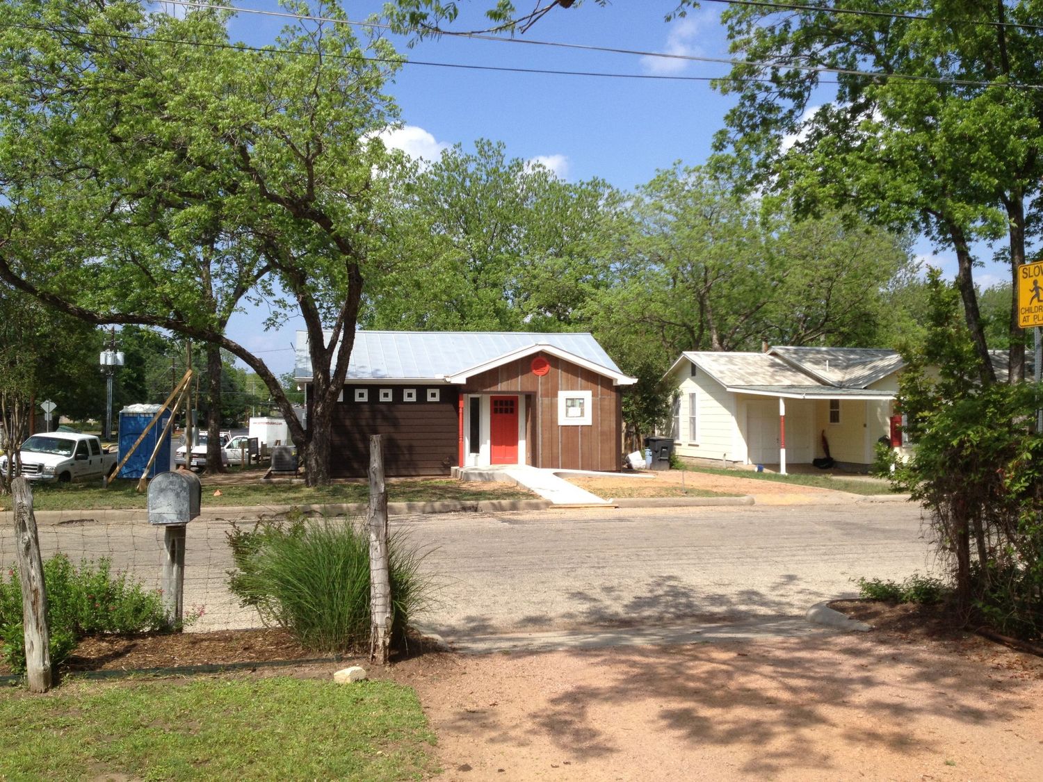 Rural property view showing multiple residential buildings and landscaping on a dirt road.