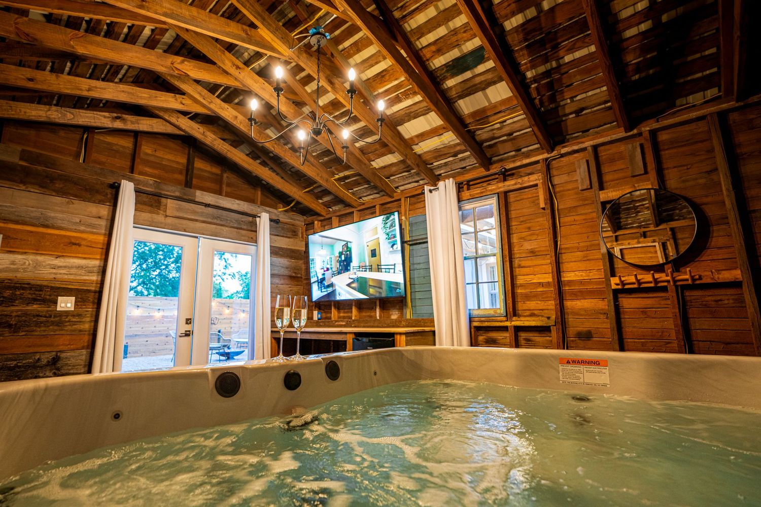 Rustic wooden beam ceiling with exposed rafters and windows in a converted barn space.