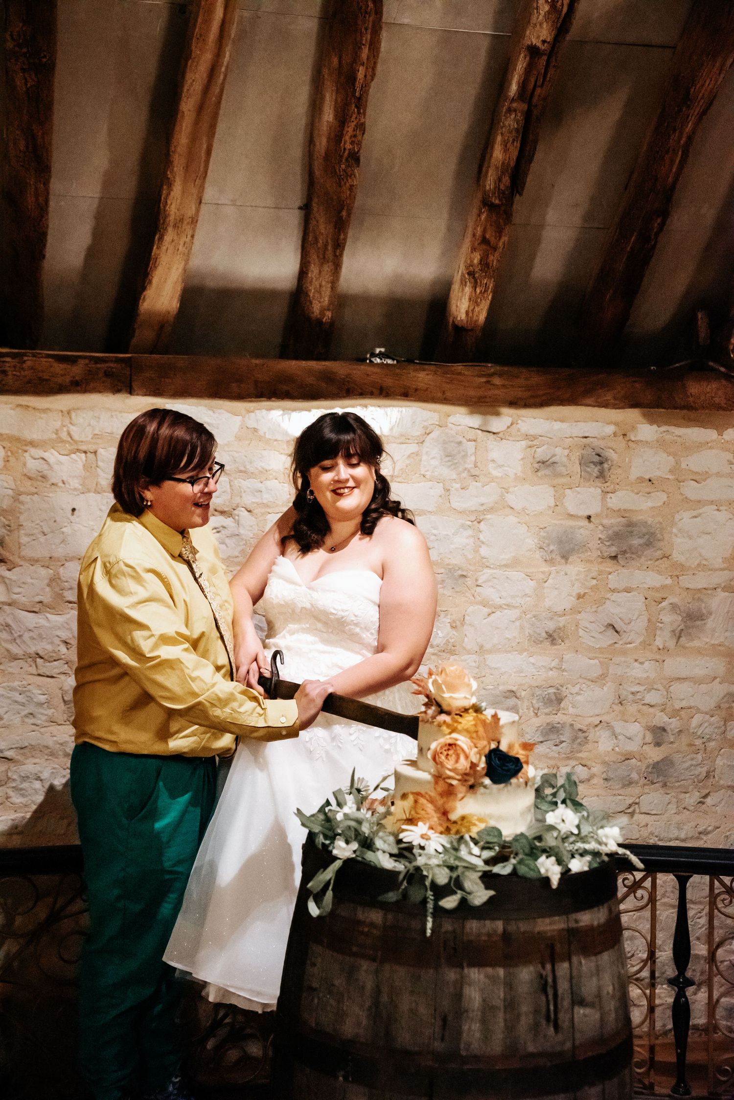 A couple shares a tender moment during their wedding ceremony in front of a rustic brick wall.