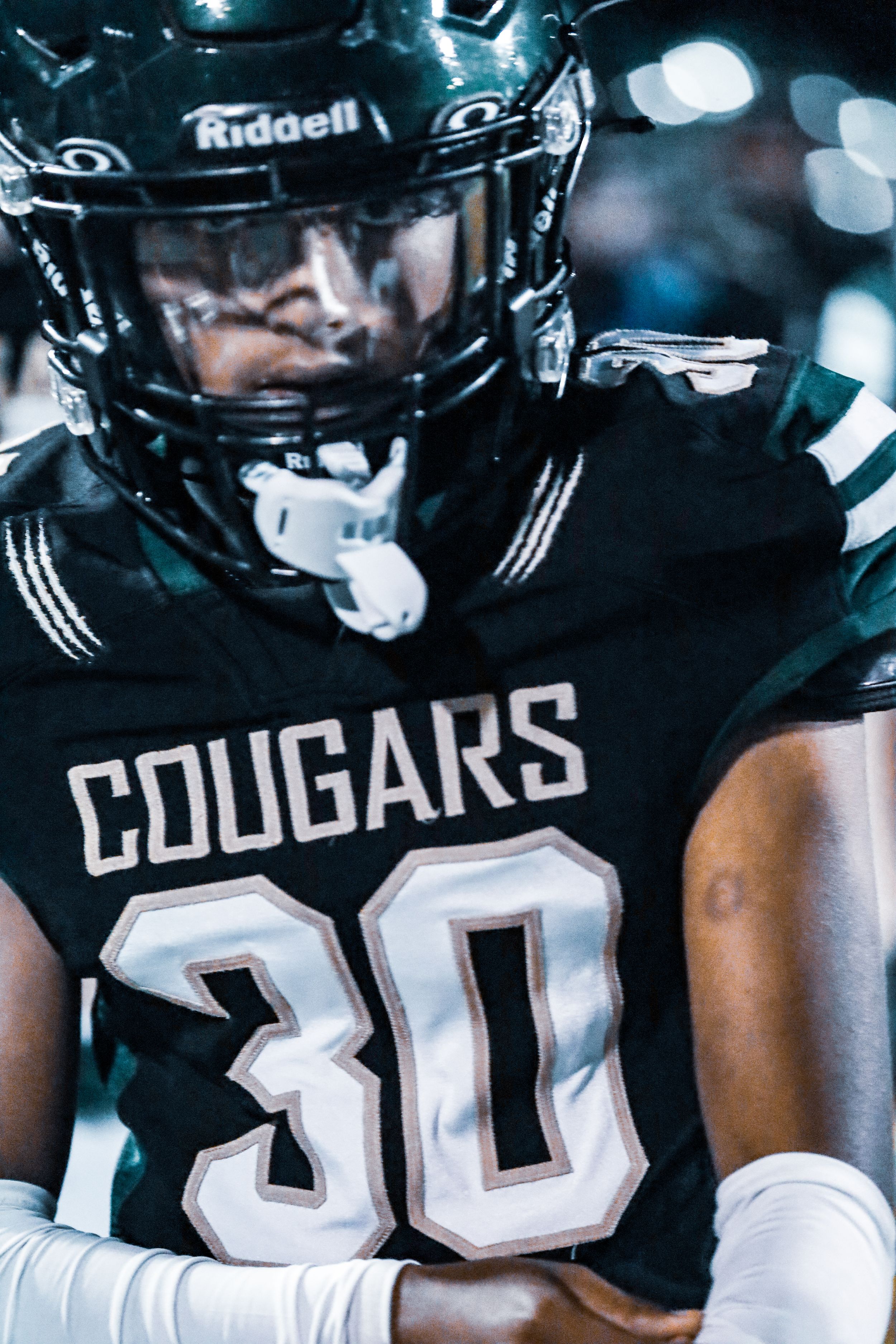 Close-up of youth football player wearing Cougars number 30 Riddell helmet and black jersey.