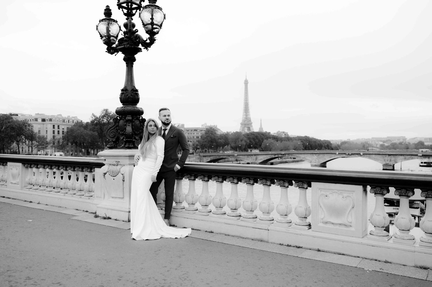 schwarz weiß bild von einem brautpaar auf einer brücke in paris mit dem eiffelturm im hintergrund