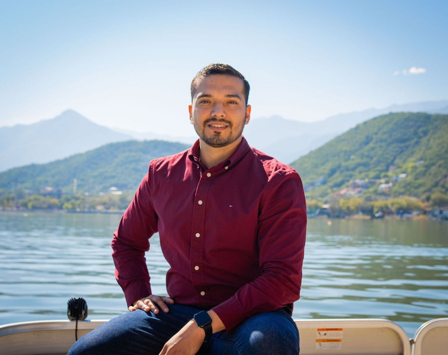 A person in a burgundy shirt sits by a scenic mountain lake on a sunny day with multiple views of the setting.